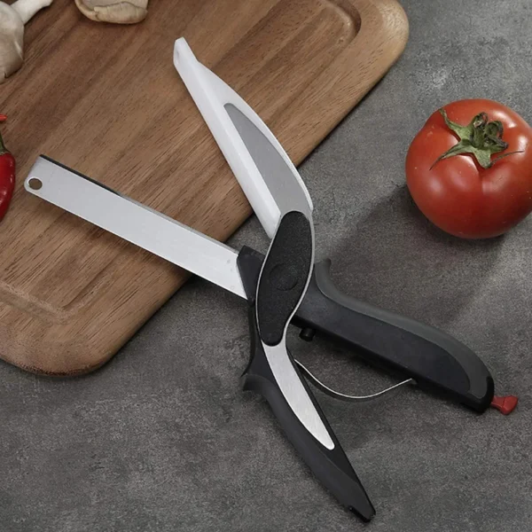 Scissors open beside a fresh tomato on a wooden surface.